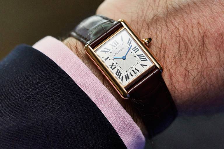 Orologio Cartier Tank indossato al polso con cinturino in pelle marrone ed eleganza classica maschile